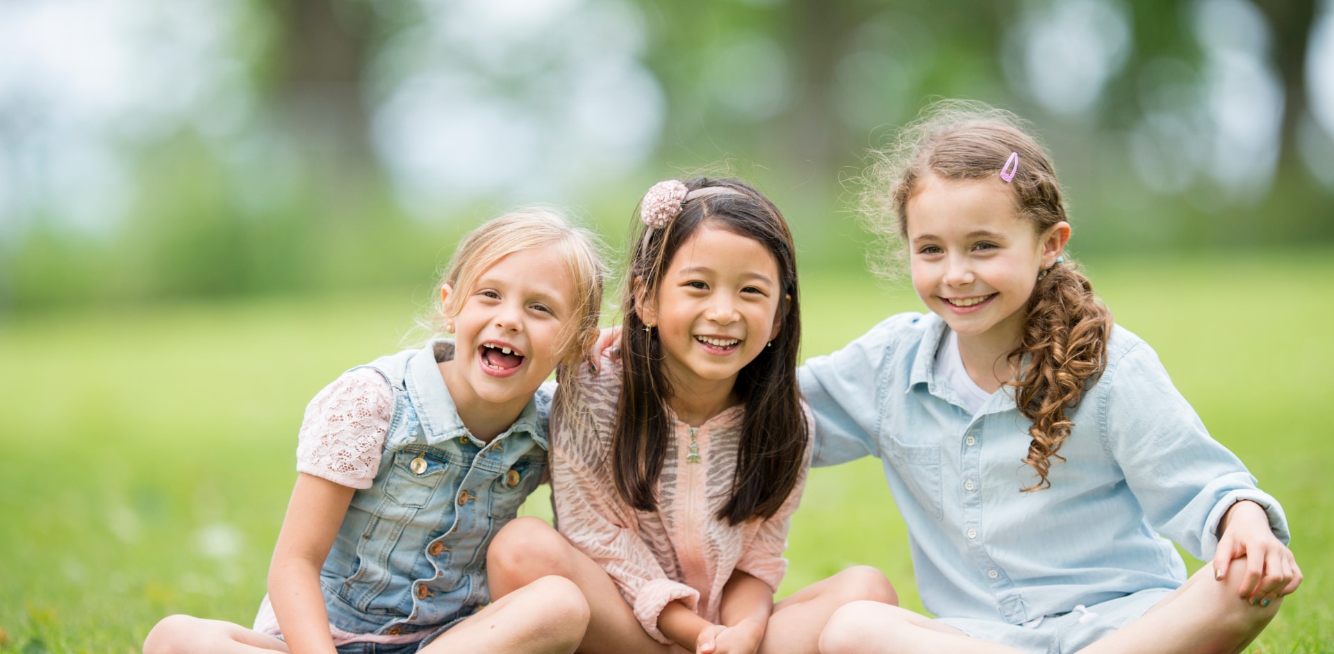 Three children smiling in a field